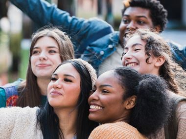 A group of smiling teenagers taking a selfie