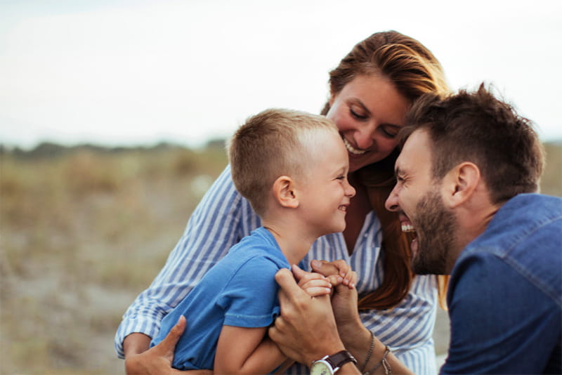 Young family playing together outside, laughing and smiling