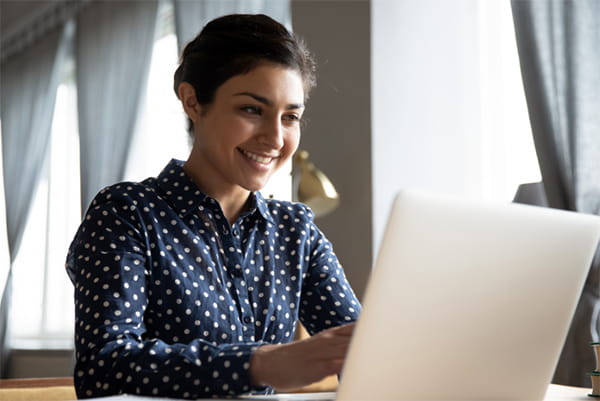 Woman smiling and working on her laptop