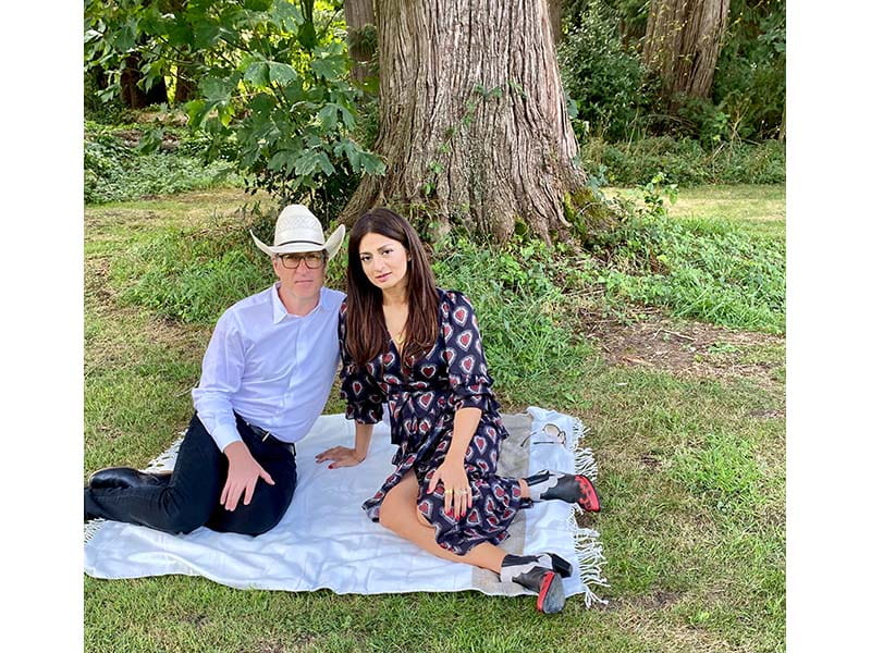 Aaron Holm and his wife, Saira, sitting on a blanket under a tree