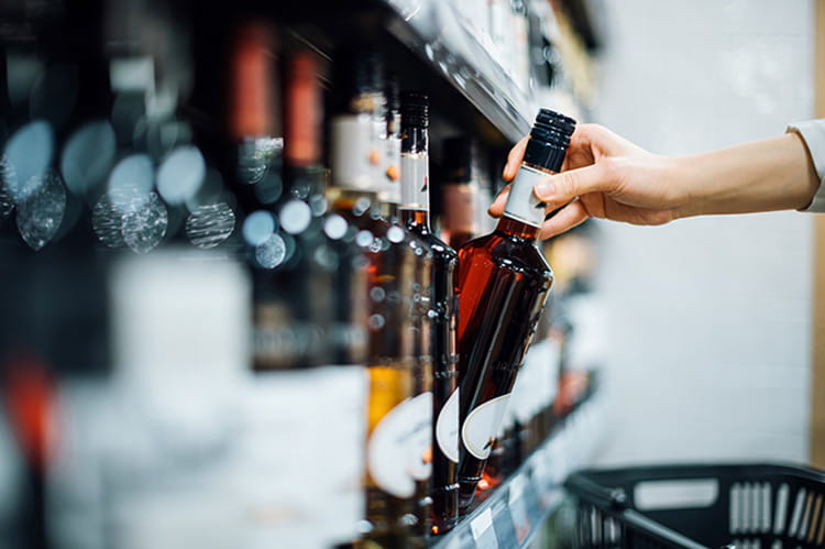 Woman shopping for a bottle of wine in a supermarket