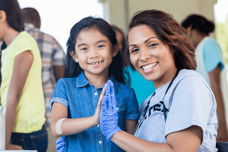 Black nurse giving young girl a high five
